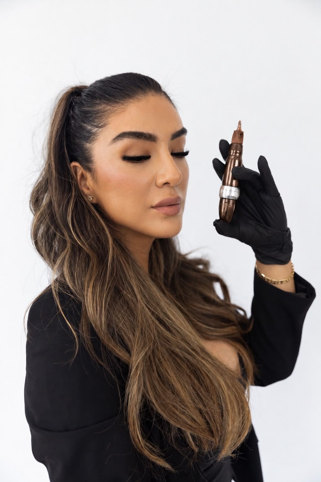 Cynthia holding a beauty device while wearing black gloves.