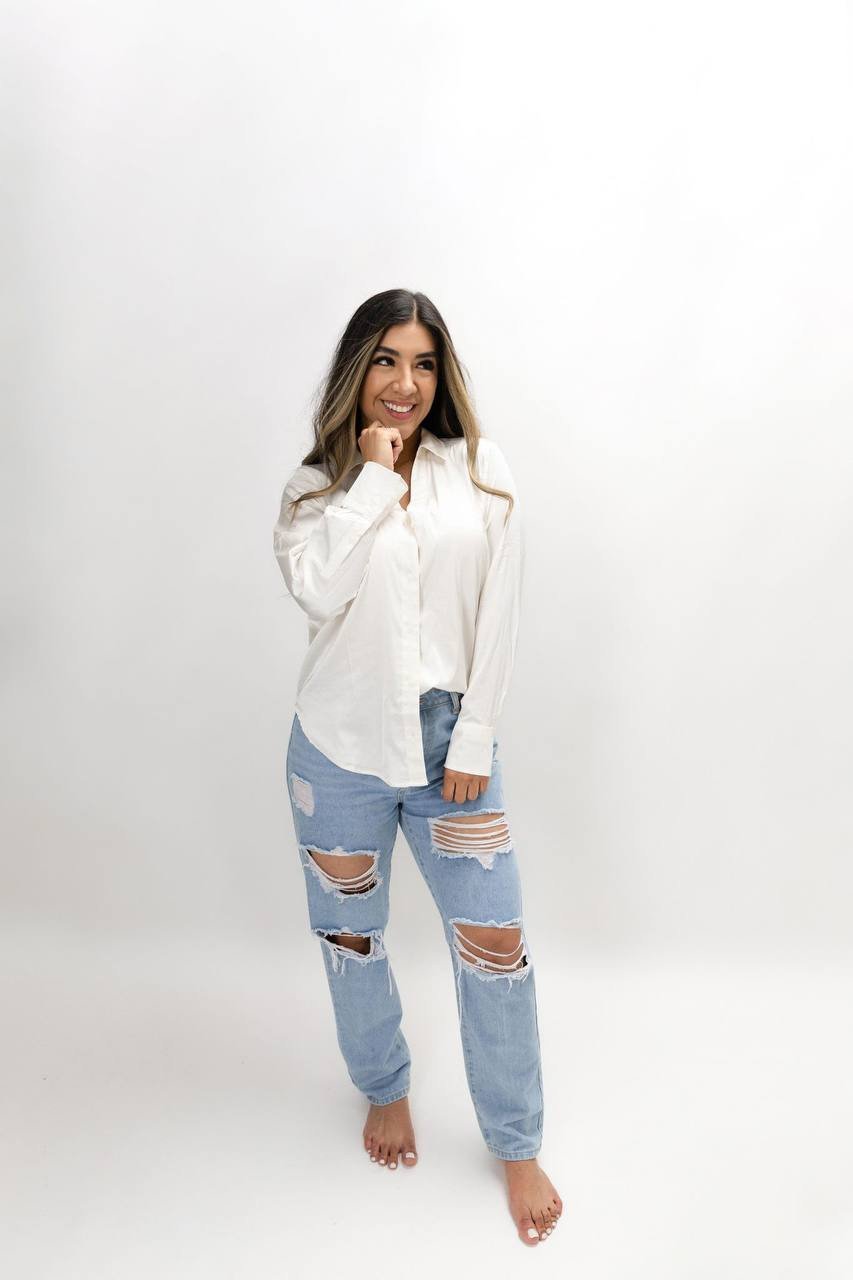 Cynthia smiling in a white blouse and blue jeans.