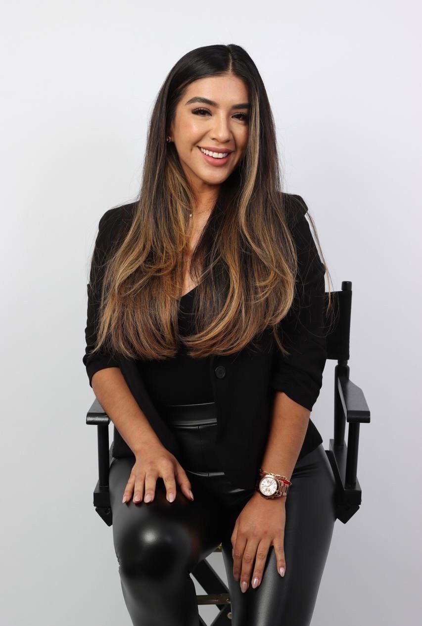 Cynthia smiling in a director’s chair, wearing black.