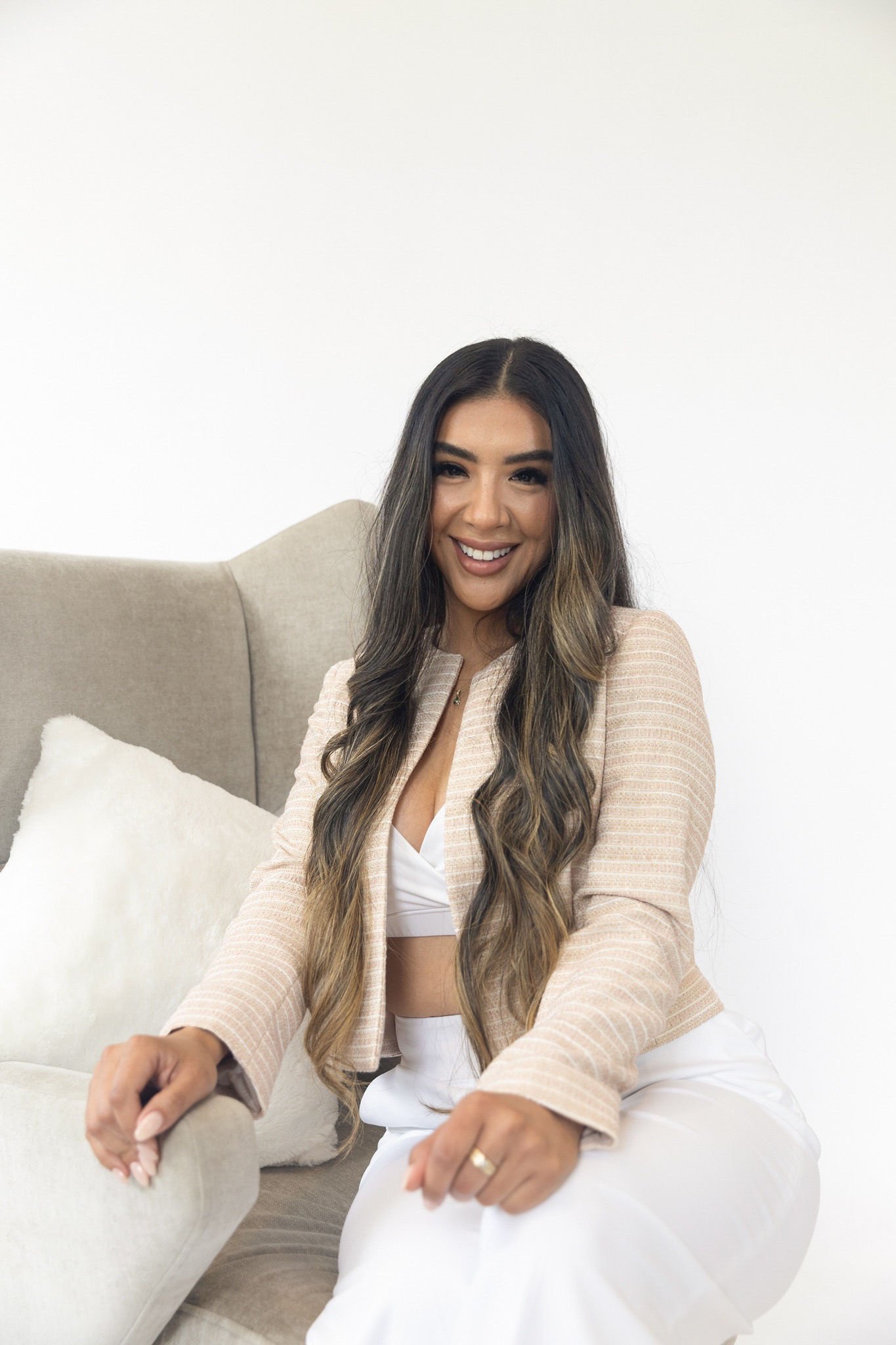 Cynthia Zapata smiling in a light jacket, seated in a cream chair.