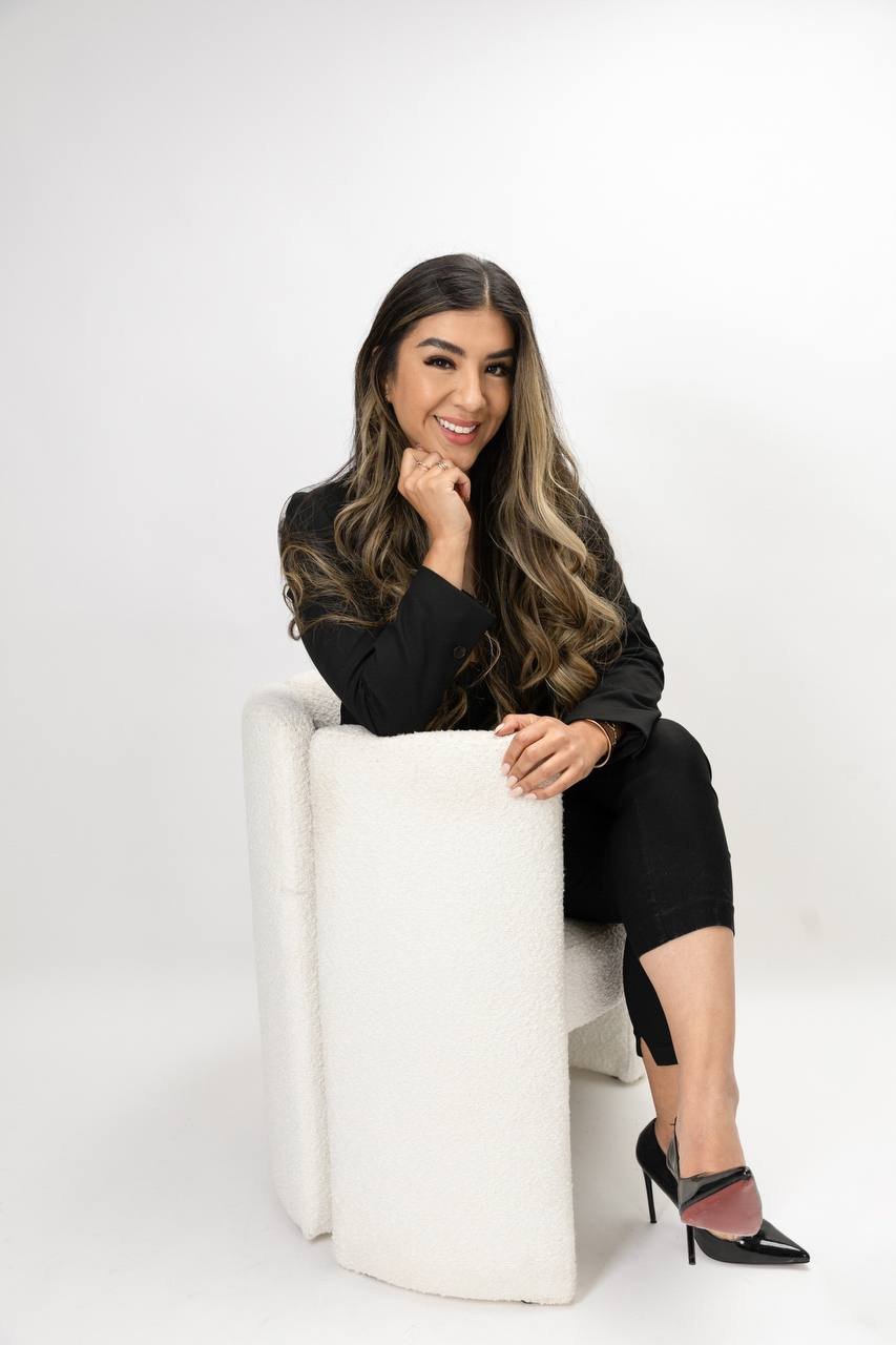 Cynthia seated in a cream chair wearing a black outfit.